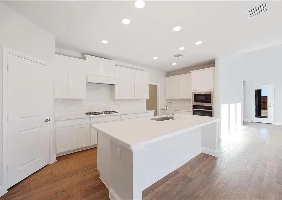 White kitchen with island, gas cooktop and built-in oven and microwave
