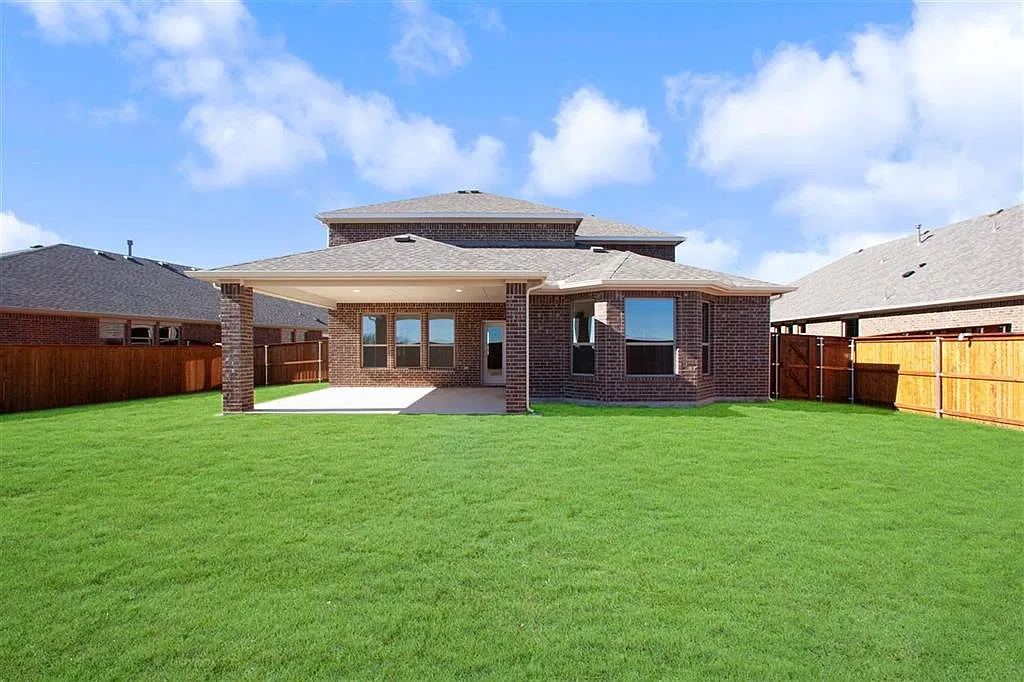 Back of home with covered patio and fenced lawn