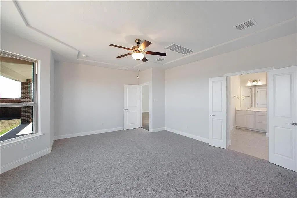 Primary bedroom with tray ceiling and doors to the primary bath